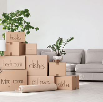 Stack of labeled cardboard moving boxes in a bright room, ready to be packed
